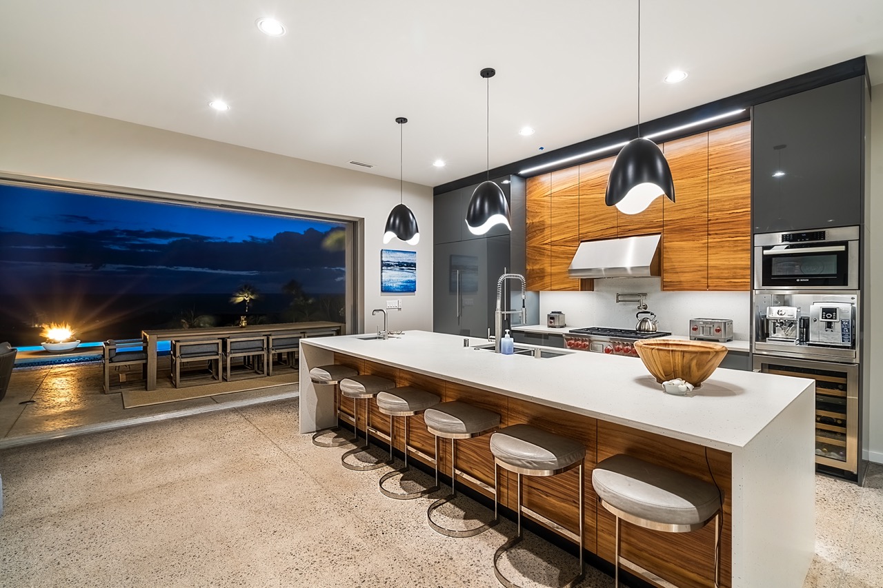 Chef's kitchen at twilight, lanai and fire beyond